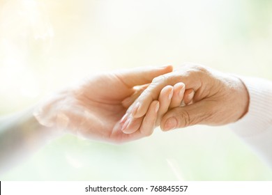 Close-up Of Young Person's Hand Holding Elderly Person's Hand As Sign Of Caring For Seniors