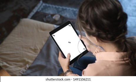 Close-up of young pretty woman with brown hair holding iPad, typing and sliding at the chroma key white screen at home. Stock footage. Smartphone new technology concept