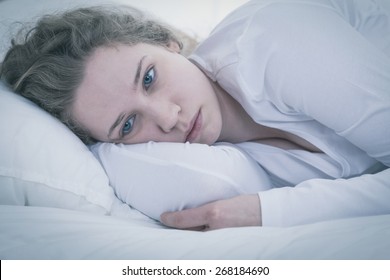 Close-up Of Young Sad Tired Woman Lying In Bed