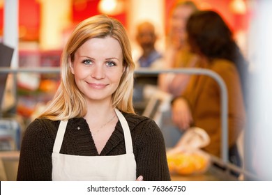 Closeup of a young shop assistant with customer in the background - Powered by Shutterstock