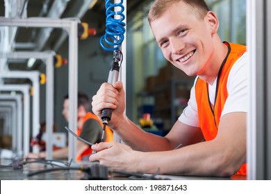 Close-up of a young smiling man working on the production line