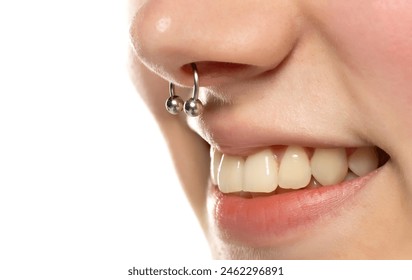 Closeup of a young smiling woman's visage with piercing septum hanging from her nose.