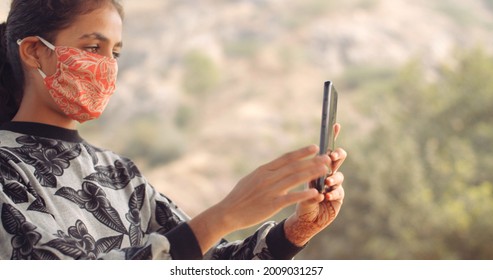 A Closeup Of A Young South Asian Girl Taking A Selfie While Wearing An Orange Covid-19 Face Mask