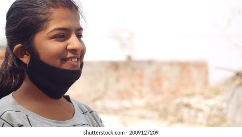 A Closeup Of A Young South Asian Girl Smiling With Her Covid Mask Pulled Down To Her Chin