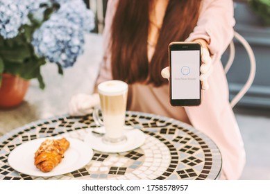 Closeup Young Stylish Woman Hold Smart Phone In Hand To Pay For Coffee And Croissant With Contactlesss Technology. Beautiful Girl Drink Coffee At Outdoor Terrace Of French Cafe. NFC Payment Checkout