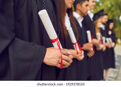 Close-up of young university graduates hands holding diplomas after university graduating outdoors, selective focus. Graduating from university or college concept
