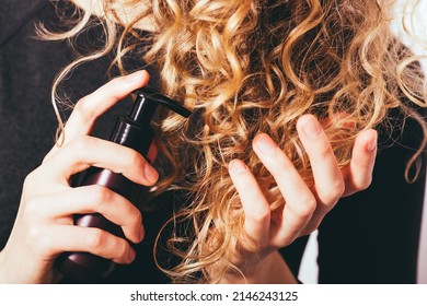 Close-up Young Woman Applying Cosmetic Treatment Oil To Her Curly Hair To Prevent Split Ends