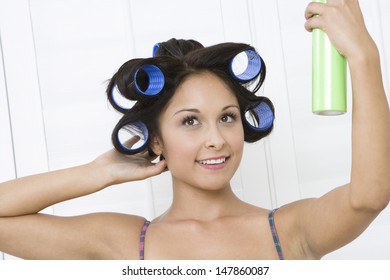 Closeup Of A Young Woman Applying Hair Spray On Curlers