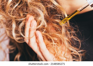 Close-up Young Woman Applying Pipette Oil To Her Curly Hair