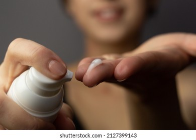 Closeup of a young woman applying prescription retinoid to her face.