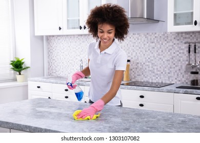 Close-up Of A Young Woman Cleaning Dirty Kitchen Counter With Spray Bottle And Napkin