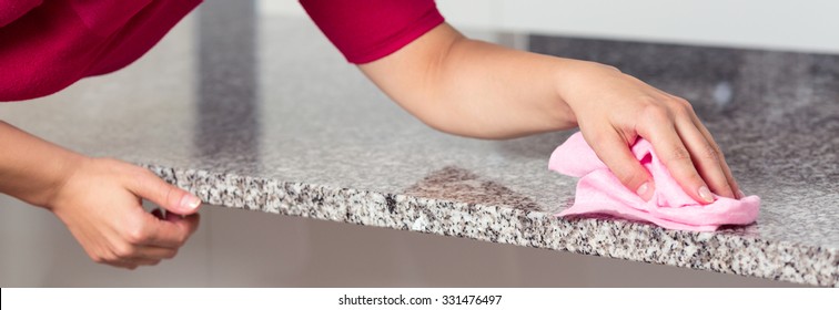 Closeup Of Young Woman Cleaning Granite Countertop