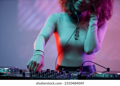 Closeup of young woman as DJ making music at turntable in neon light - Shutterstock ID 2310484049