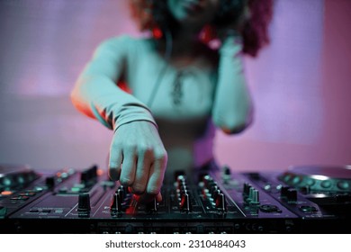 Closeup of young woman as DJ turning switches on mixer in nightclub, copy space - Shutterstock ID 2310484043