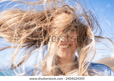 Closeup of young woman face covered with flying hair in windy day. Portrait female with hair blowing in the wind. Wanderlust autumn travel, atmospheric moment