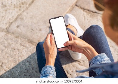 Closeup of young woman hand holding mobile phone with blank screen. Top view of girl using smartphone sitting on the stairs outside. High angle view of african woman unlocking cellphone.