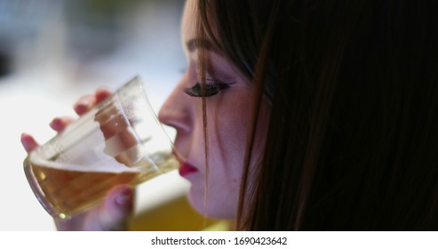 
				Closeup of young woman hand using cellphone touchscreen while drinking alcholic beverage at bar nightlife
