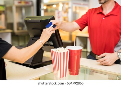 Closeup Of A Young Woman Handing Over Her Credit Card To Pay For Some Snacks At The Concession Stand In A Movie Theater