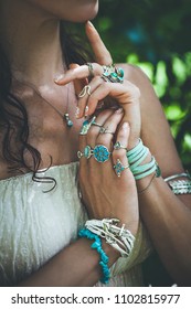 closeup of young woman hands lot of boho style jewelry, rings and bracelets outdoor summer day