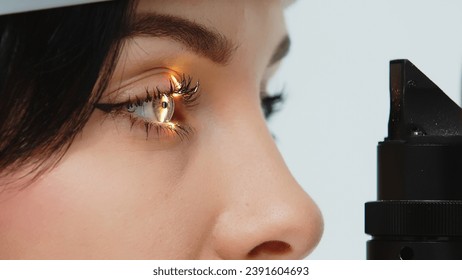 Close-up of a young woman having her vision tested on an ophthalmology diagnostic vision testing equipment. Professional ophthalmological apparatus. - Powered by Shutterstock