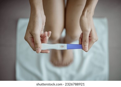 Close-up of young woman holds a pregnancy test in her hands. Positive pregnancy test. - Powered by Shutterstock