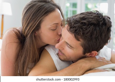 Close-up Of A Young Woman Kissing Man In Bed At Home