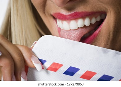 Close-up Of A Young Woman Licking An Envelope