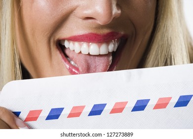 Close-up Of A Young Woman Licking An Envelope