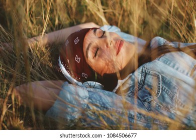 Closeup of young woman listens to music and lying in the meadow 