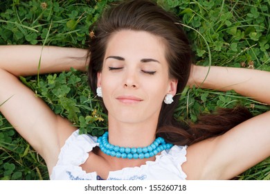 Closeup Of Young Woman Lying Down On Grass With Eyes Closed