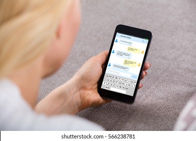 Close-up Of A Young Woman Sending Text Message Using Mobile Phone At Home