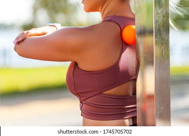 Closeup Young Woman Shoulders In Tight Top Leaning On Small Ball Against Wall To Fix Back Ache, Massaging Stiff Muscles And Sore Neck, Exercise To Relieve Spinal Pain. Relaxation And Muscle Stretching