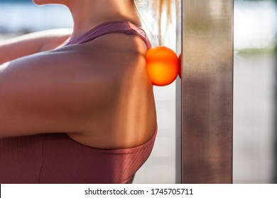 Closeup Young Woman Shoulders In Tight Top Leaning On Small Ball Against Wall To Fix Back Ache, Massaging Stiff Muscles And Sore Neck, Exercise To Relieve Spinal Pain. Relaxation And Muscle Stretching