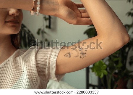 Close-up of a young woman showing a tattoo on her arm.