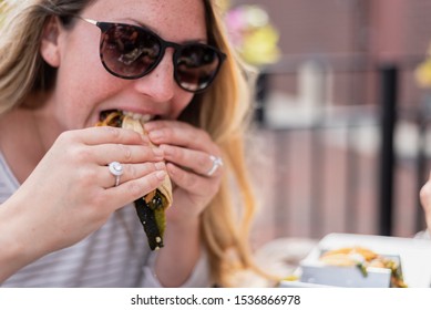 Closeup Of A Young Woman Sitting Outdoors Eating Tacos In Summer