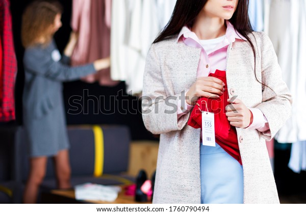 Closeup of young woman is stealing red jeans in\
store, shop, boutique at shopping center. Girl is hiding unpaid\
good under clothes. Seller, assistant caught thief on hot.\
Shoplifting concept.