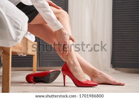 Close-up of a young woman suffering from leg pain sitting in red shoes Stock photo © 