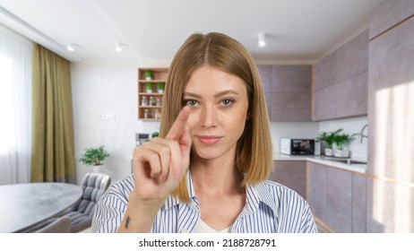 Close-up of young woman swipes finger at display of phone. Female over living room at home - Shutterstock ID 2188728791