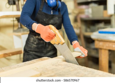 Closeup Of A Young Woman Using A Hand Saw To Cut Some Wood In A Woodshop