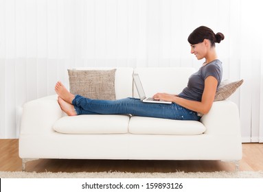 Close-up Of Young Woman Using Laptop On Couch