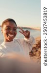 Close-up of young woman waving and laughing looking at the mobile phone camera in the sunlight, selfie