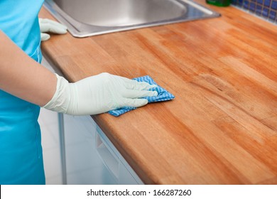 Closeup Of Young Woman Wearing Apron Cleaning Kitchen Worktop