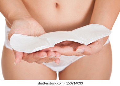 Close-up Of Young Woman Wearing Lingerie Holding Sanitary Pad Over White Background