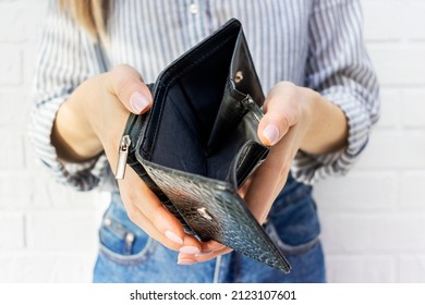 Close-up Of A Young Womans Hand Holding An Empty Purse. No Money In The Wallet. Bankruptcy, Financial And Debt Problems, Crisis, Unemployment, Lack Of Funds To Pay Expenses And Loan Credit Card.