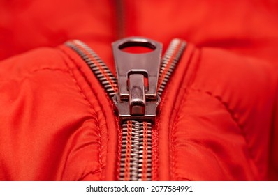 Close-up zipper on light red clothing, jacket. Zipper closure with lock.
