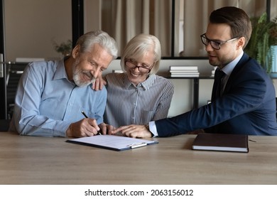 Closing deal. Happy satisfied husband wife retirees put own signatures under life insurance policy sale purchase contract at lawyer consultant office. Aged couple visit bank manager to make deposit