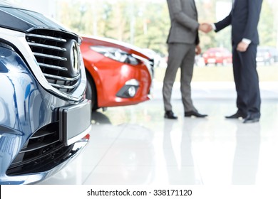 Closing the deal. Selective focus on the car customer shaking hands with dealer on the background