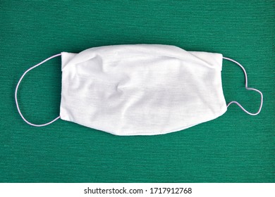 Cloth Bandage Or Face Mask To Protect The Respiratory System During The Covid-19 Pandemic, On A Green Background. Reusable Microfiber Facemask, Subject To Daily Washing.