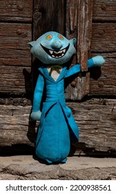 Cloth Puppet In Blue Frock Coat, In The Background A Very Worn Wooden Door.
