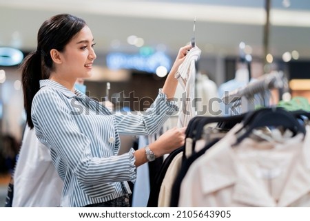 cloth shopping,asian cheerful smiling while choosing cloth from rack standing In Clothing Store at department store,Asian woman is buying clothes